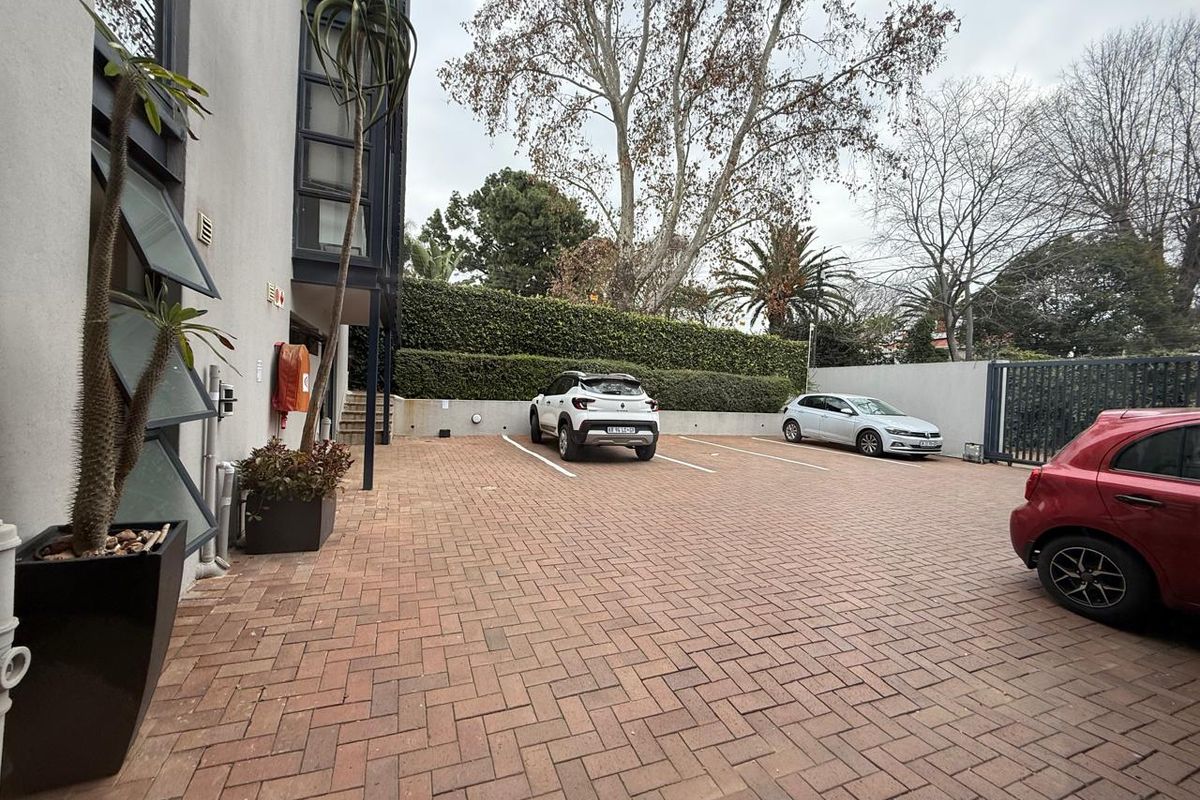 A paved outdoor parking area adjacent to the office building, featuring marked parking bays and secure perimeter fencing.