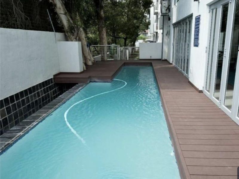 A well-maintained lap pool featuring modern composite decking and direct access to the apartment via large bi-fold doors.