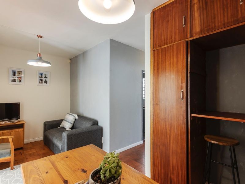 A living area featuring classic parquet flooring, built-in wooden storage cabinetry, and modern pendant lighting fixtures.