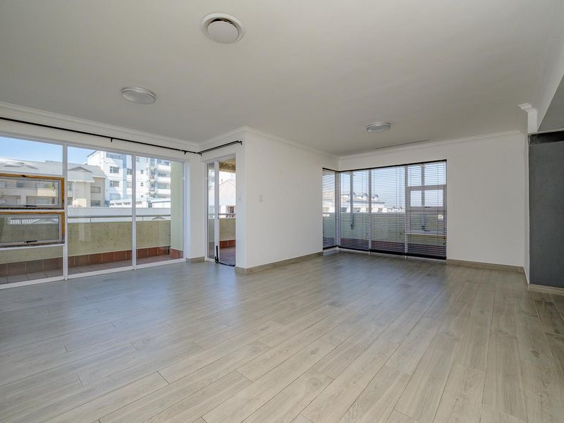 Spacious, light-filled living area featuring modern laminate flooring, large sliding glass doors leading to a balcony, and neutral finishes throughout.