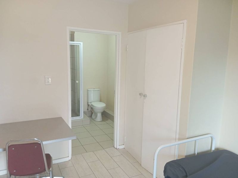 Bedroom featuring tiled flooring, a built-in cupboard, and an en-suite bathroom equipped with a toilet and shower cubicle.