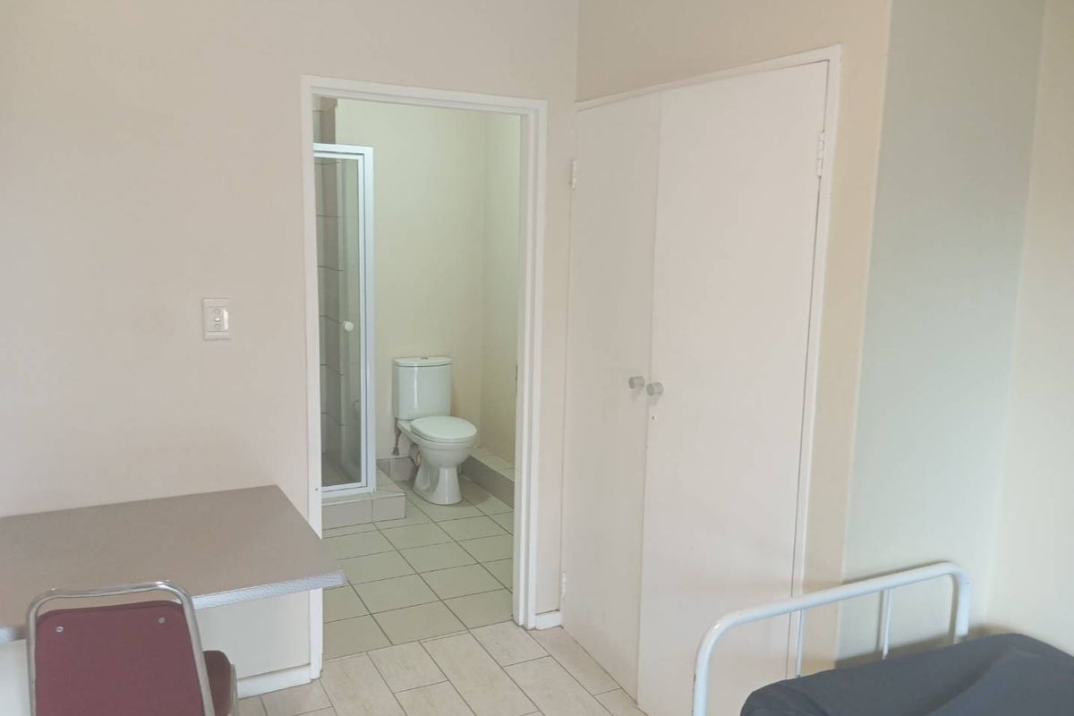 Bedroom featuring tiled flooring, a built-in cupboard, and an en-suite bathroom equipped with a toilet and shower cubicle.