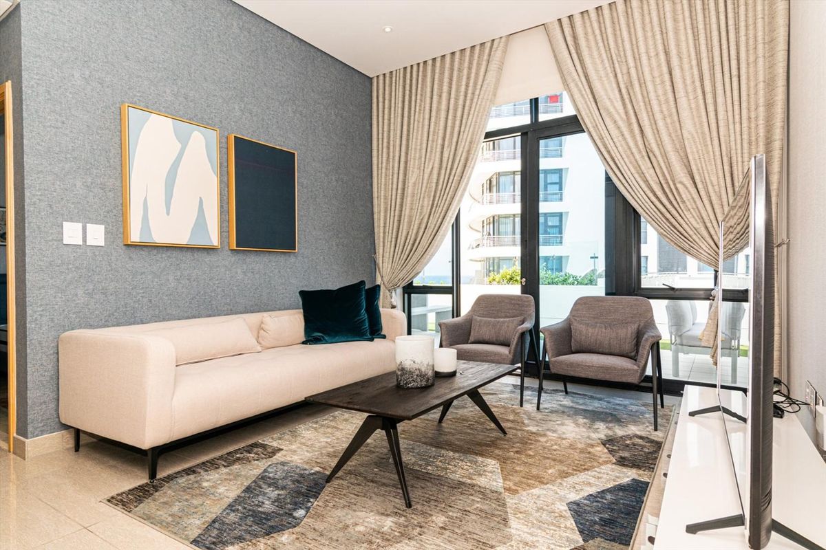 Modern living room featuring tiled flooring, textured feature wall, and large sliding glass doors providing access to the balcony.