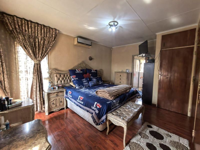 Spacious bedroom featuring laminate flooring, a built-in cupboard, and a wall-mounted air conditioning unit.