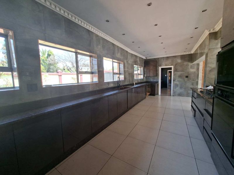 Spacious kitchen featuring extensive dark cabinetry, granite countertops, tiled walls, and built-in oven, offering a clean and modern aesthetic.