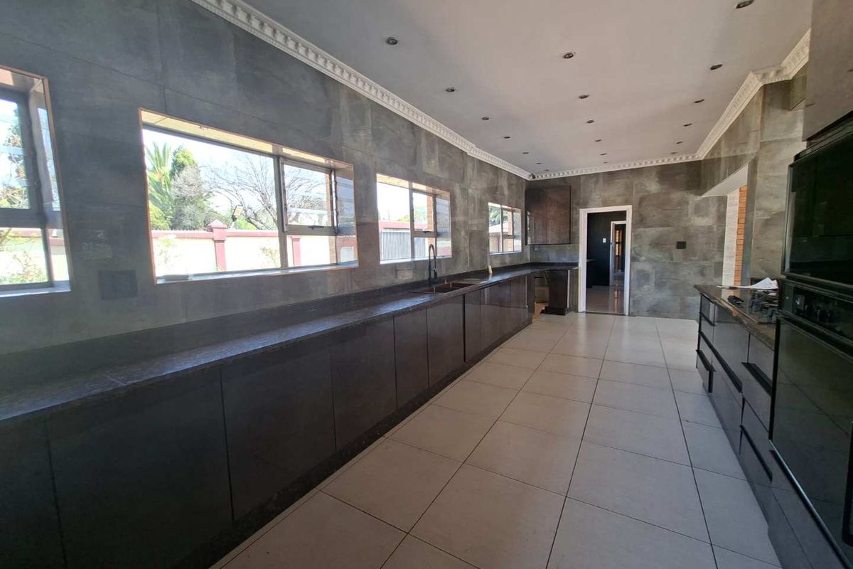 Spacious kitchen featuring extensive dark cabinetry, granite countertops, tiled walls, and built-in oven, offering a clean and modern aesthetic.