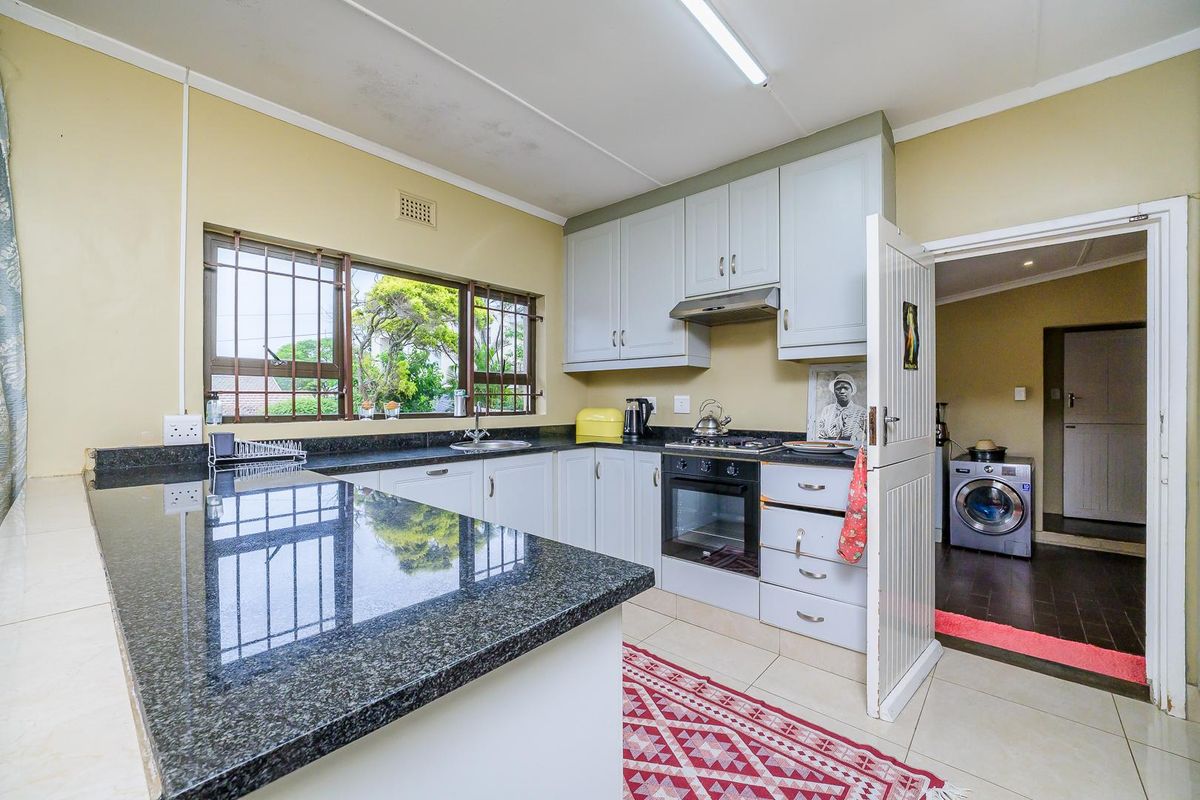 A functional kitchen featuring granite countertops, built-in cabinetry, a gas hob, and an integrated oven, with an adjacent laundry area visible.