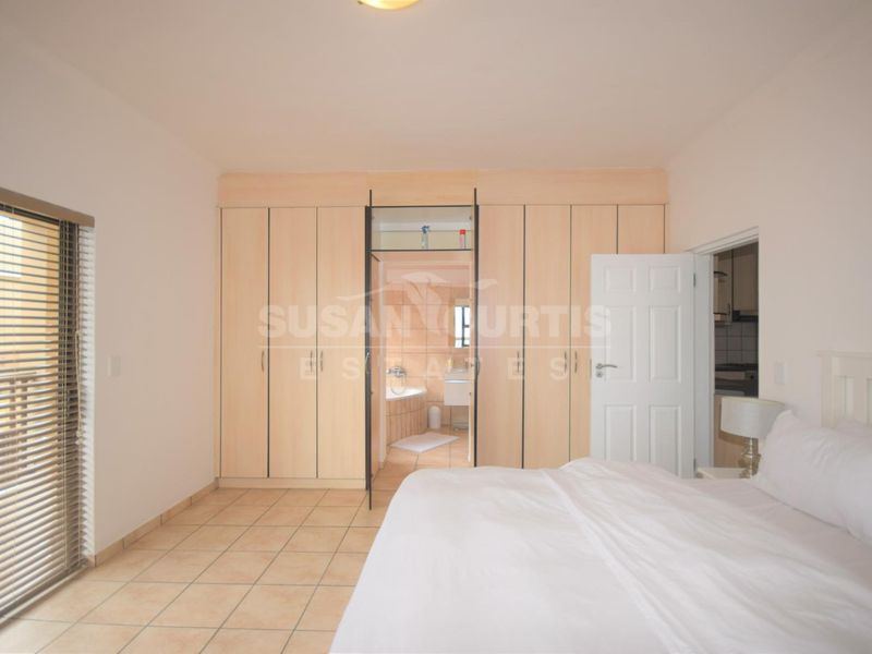 Spacious bedroom featuring built-in cupboards, tiled flooring, and direct access to an en-suite bathroom.