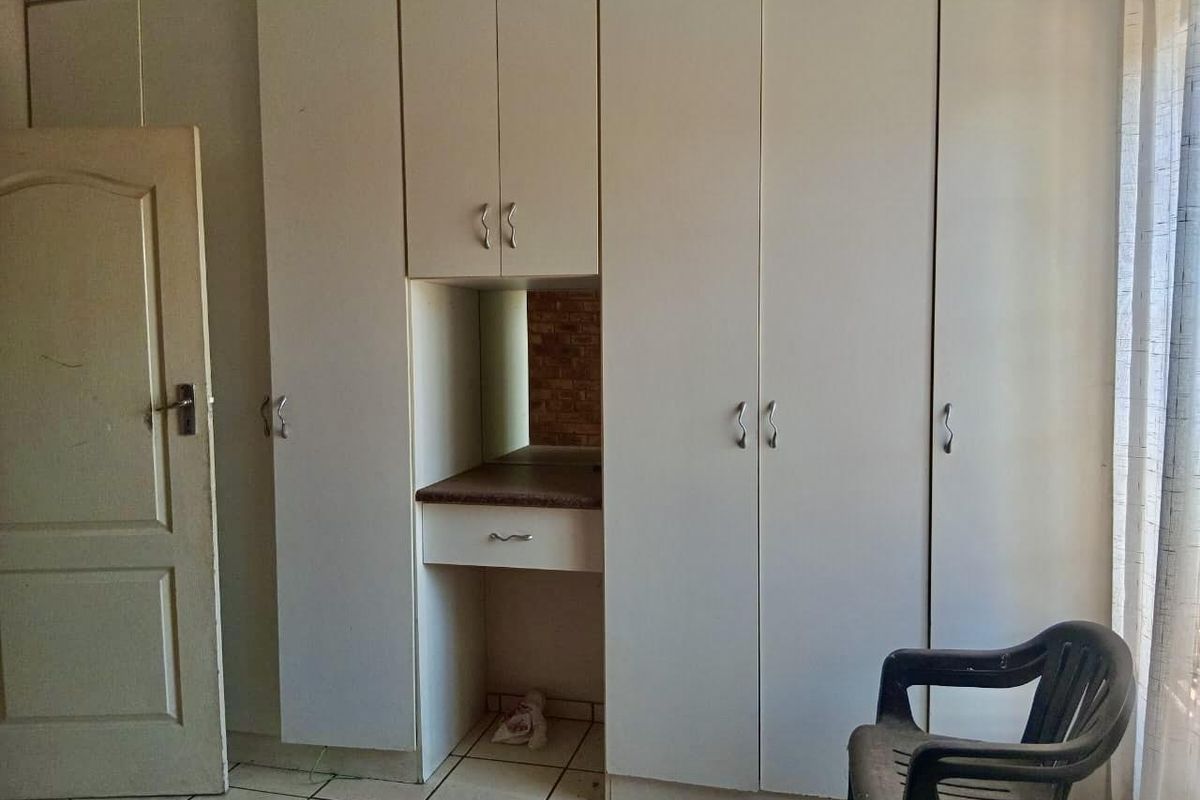 Bedroom featuring floor-to-ceiling built-in cupboards with an integrated vanity station and tiled flooring.