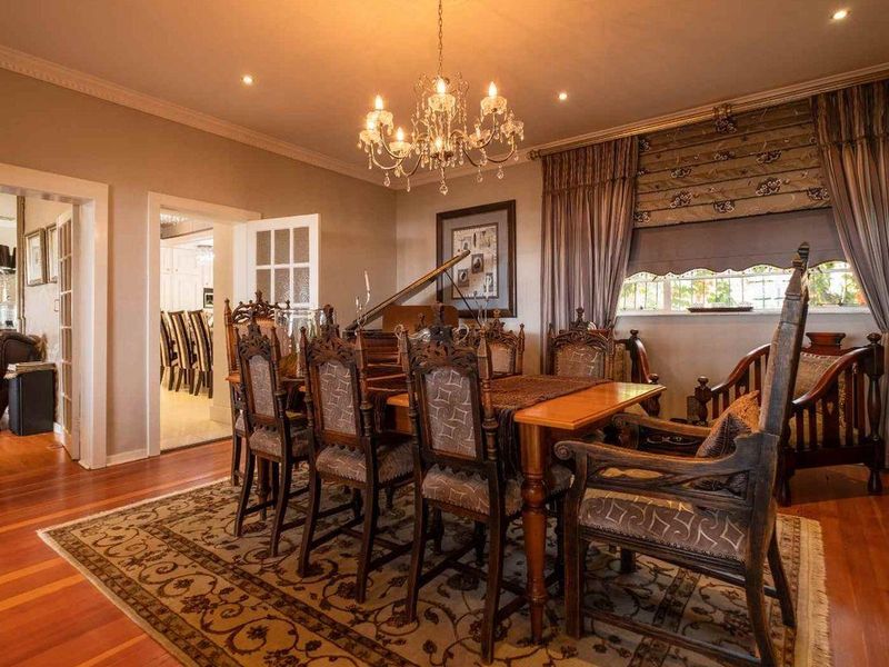 Formal dining room featuring polished hardwood flooring, crown molding, recessed lighting, and an elegant chandelier, with access to adjacent living spaces via french doors.