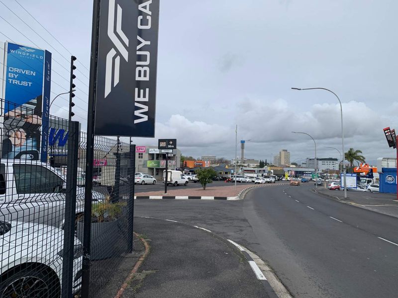 A street-level view of a commercial area featuring asphalt roads, sidewalks, and prominent business signage.