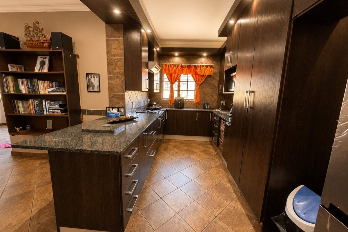 A well-appointed kitchen featuring dark wood cabinetry, granite countertops, tiled flooring, and integrated appliances with recessed lighting.