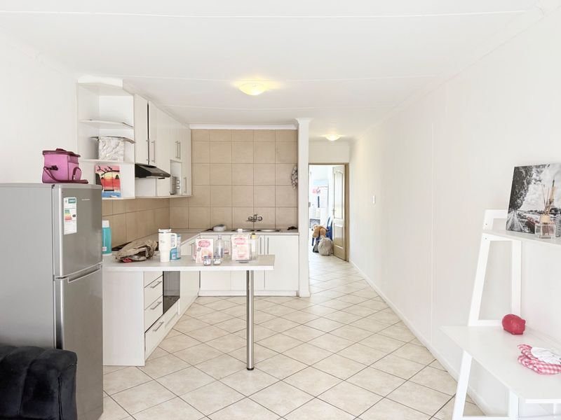 Functional kitchen featuring white cabinetry, tiled backsplash, and ceramic flooring, offering a clean and practical layout for daily meal preparation.