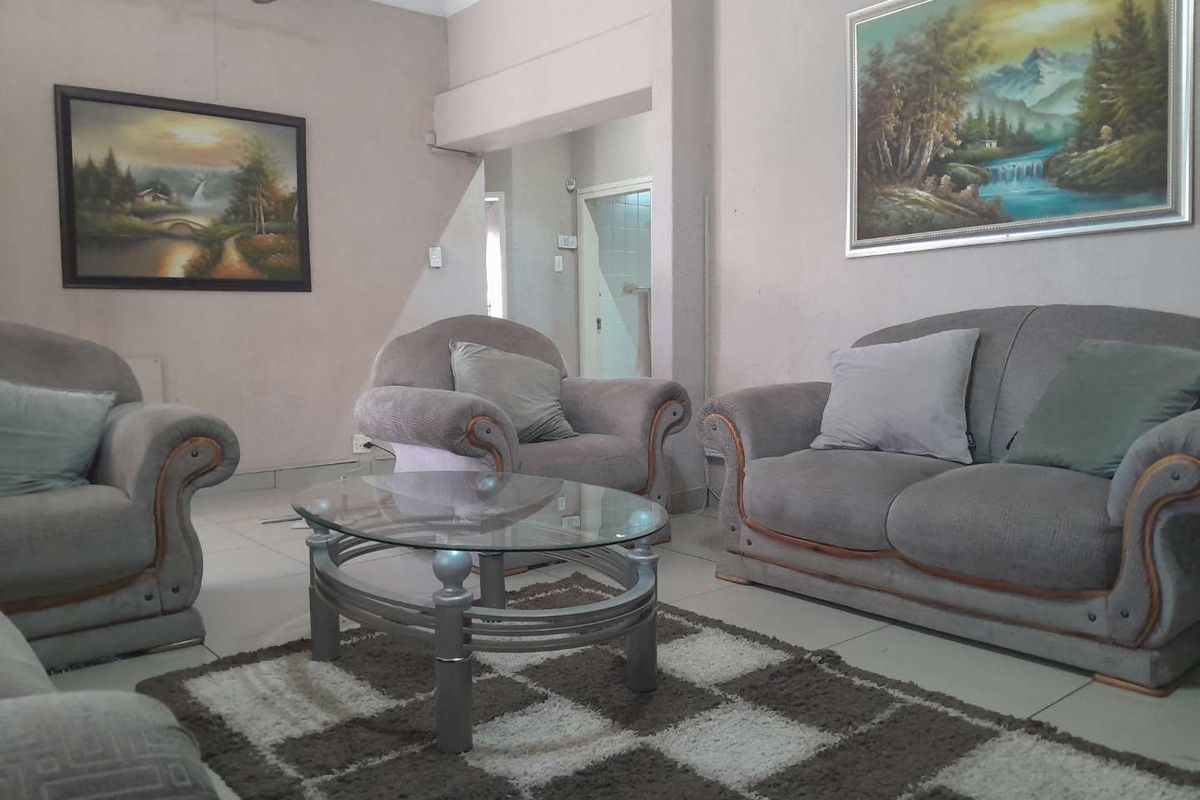 A living room featuring tiled flooring, coving, and a ceiling fan, providing a functional and neutral space for relaxation.