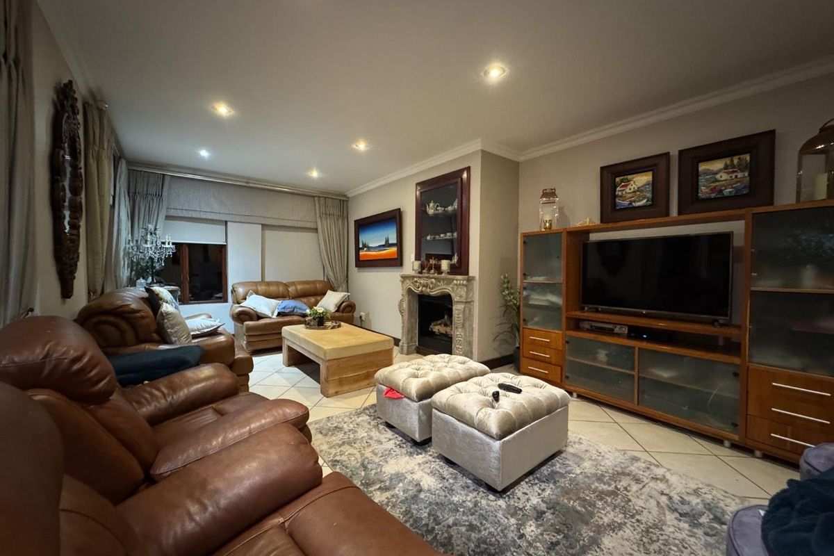 A spacious living room featuring a decorative stone fireplace, tiled flooring, and recessed ceiling lighting.
