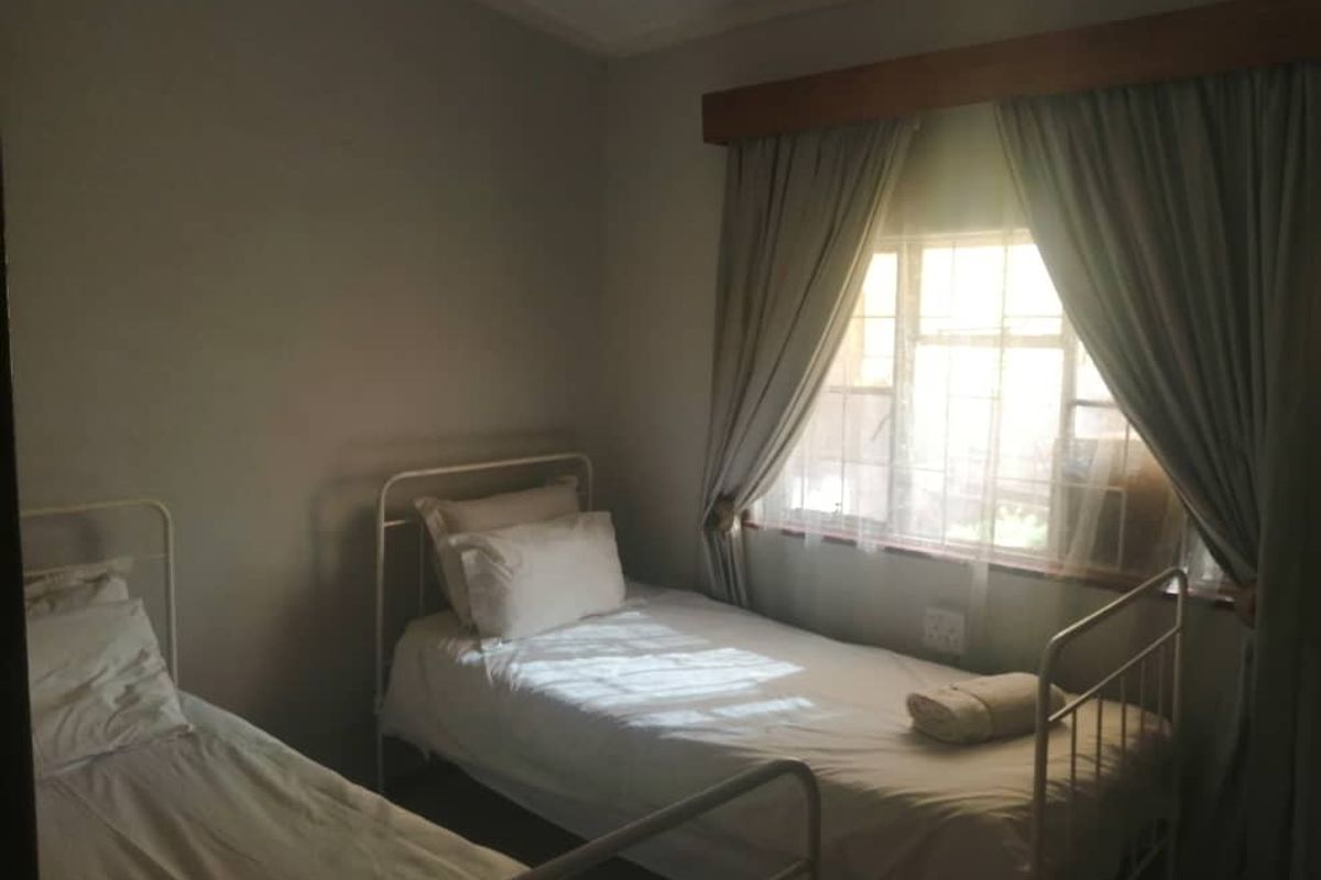 A functional bedroom featuring a window with fitted curtain rails and natural light, providing a simple and comfortable sleeping space.