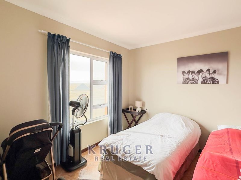 A functional bedroom featuring tiled flooring and a large window that allows for natural light.