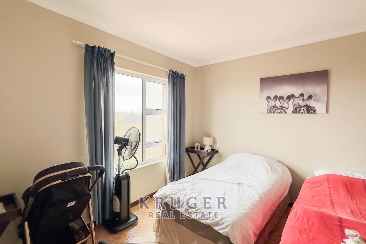 A functional bedroom featuring tiled flooring and a large window that allows for natural light.