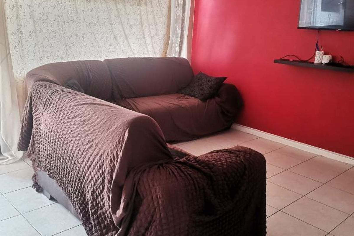 A living room featuring tiled flooring and a bold red accent wall, providing a functional space for relaxation.