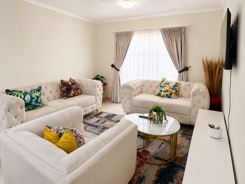 A well-lit living room featuring neutral walls, tiled flooring, and large windows with installed curtain tracks.