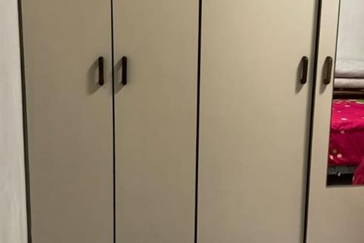A bedroom featuring floor-to-ceiling built-in cupboards with integrated mirror and tiled flooring.
