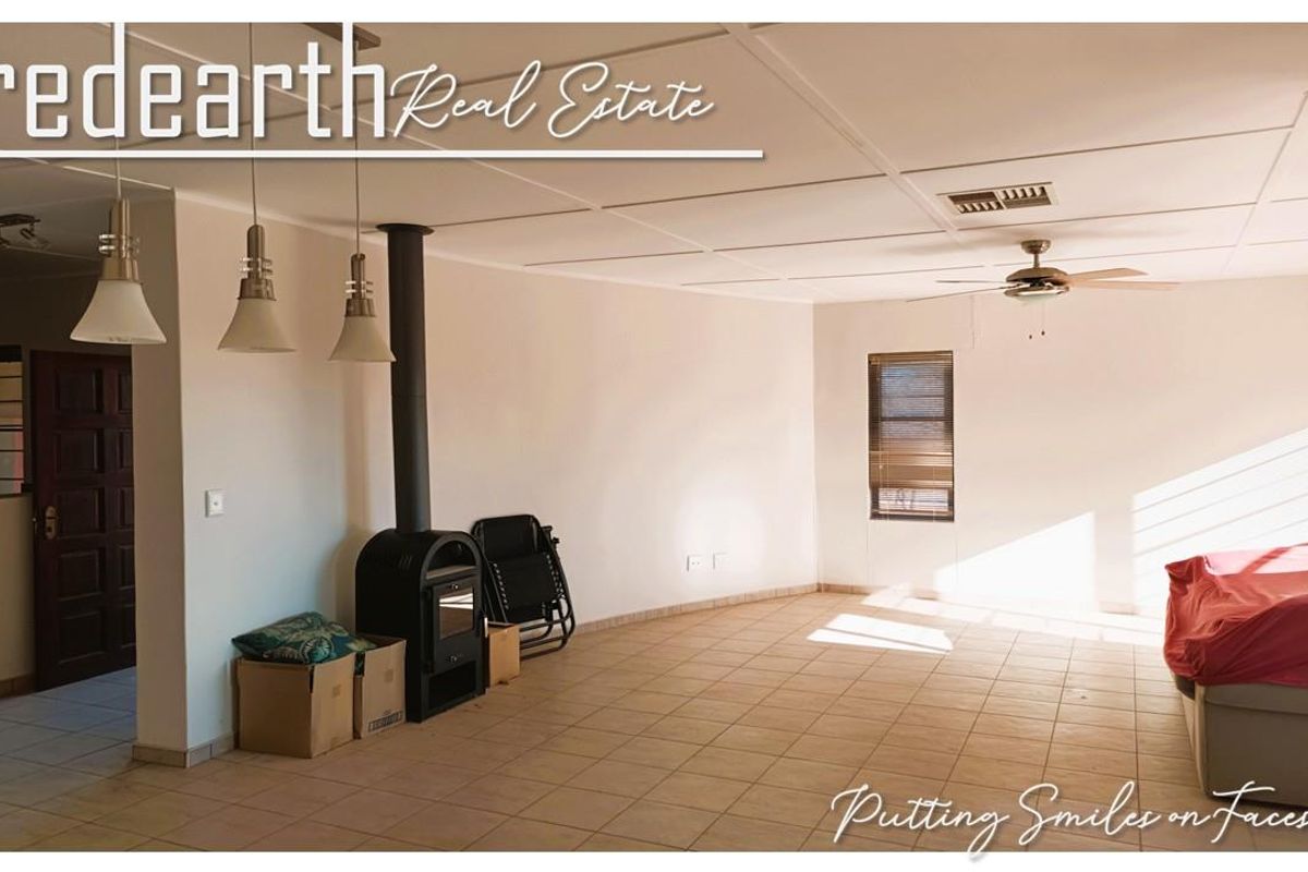 Spacious living area featuring tiled flooring, a freestanding fireplace, ceiling fan, and pendant lighting, offering a bright and functional space.