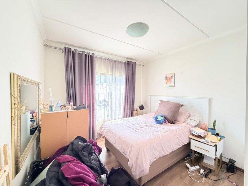 A functional bedroom featuring laminate flooring, a ceiling light fixture, and a curtain rod, providing a comfortable space for rest.