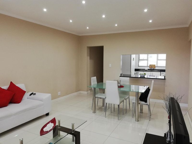Open-plan living and dining area featuring tiled flooring, recessed downlighting, and a convenient pass-through window connecting to the kitchen.