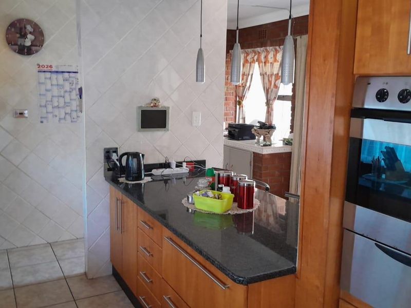 A functional kitchen featuring wooden cabinetry, granite countertops, a built-in oven, and tiled finishes, offering a practical layout for daily meal preparation.