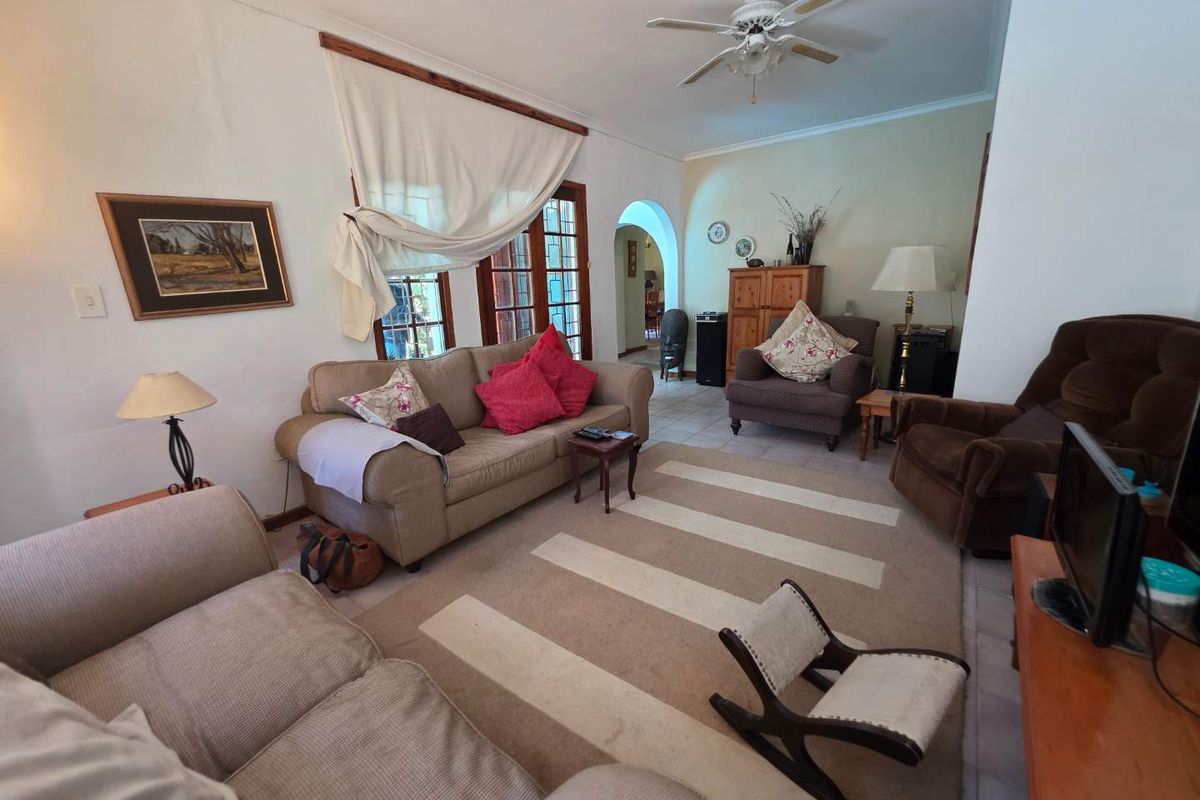 A spacious living room featuring tiled flooring, a ceiling fan, and an arched doorway leading to adjacent living areas.