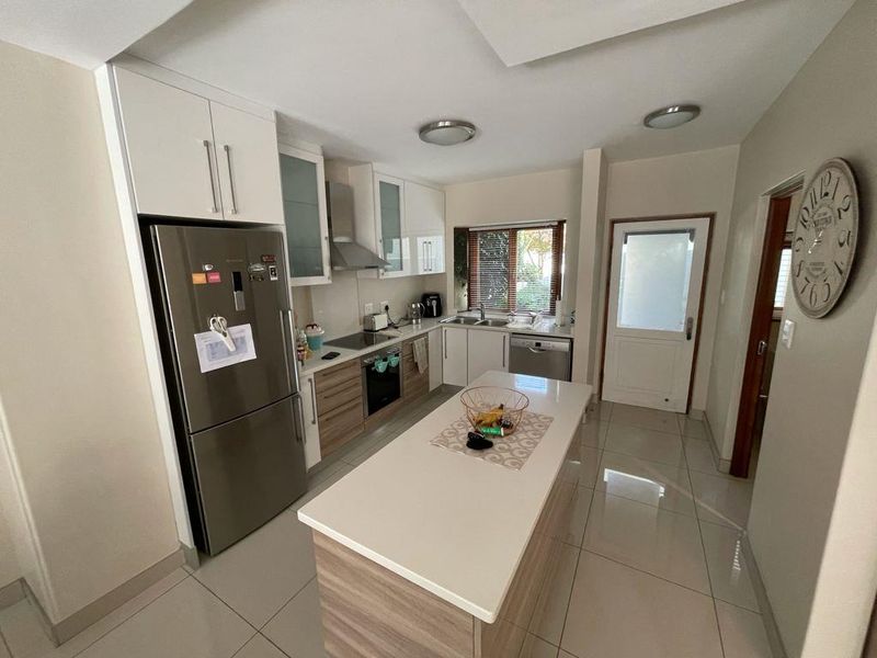 Modern kitchen featuring a central island, built-in cabinetry, stainless steel appliances, and tiled flooring, offering a functional and well-lit workspace.