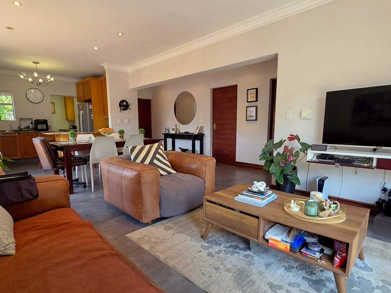 Spacious open-plan living and dining area featuring tiled floors, recessed lighting, and a functional kitchen with wooden cabinetry.