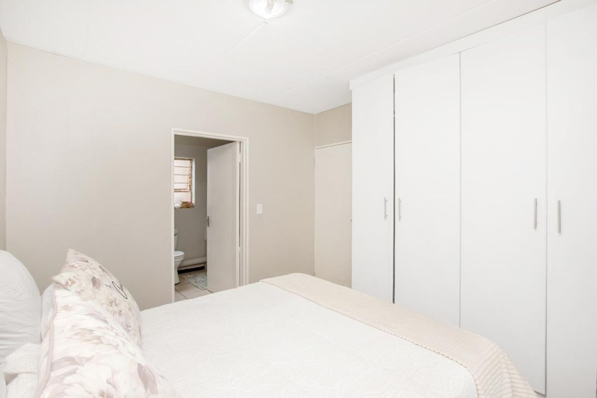 A bedroom featuring built-in white cabinetry and an adjoining en-suite bathroom with neutral wall finishes.