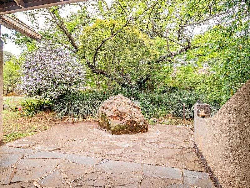 A covered patio area featuring natural flagstone paving and a garden outlook, providing a tranquil outdoor space for relaxation.
