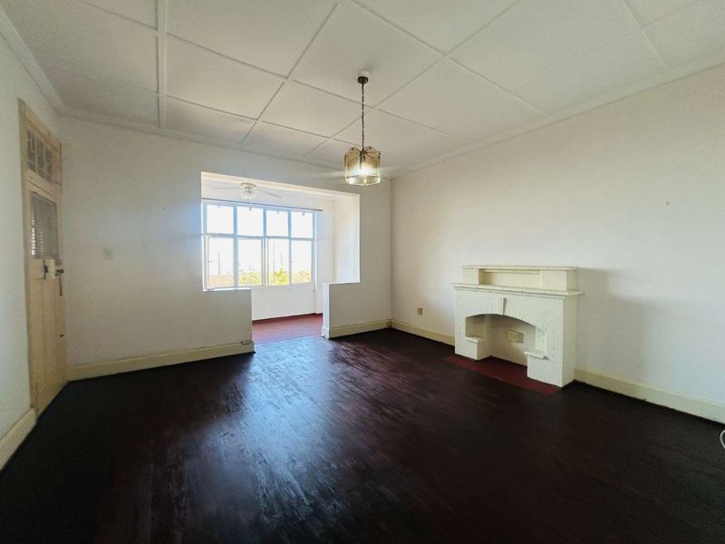 Spacious living room featuring dark hardwood flooring, a classic fireplace, and a tiled ceiling, offering a bright and open layout.