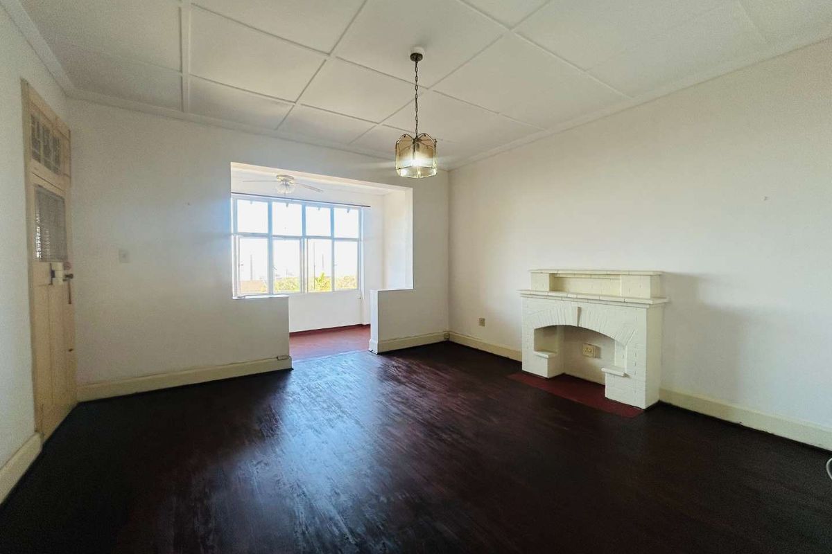 Spacious living room featuring dark hardwood flooring, a classic fireplace, and a tiled ceiling, offering a bright and open layout.