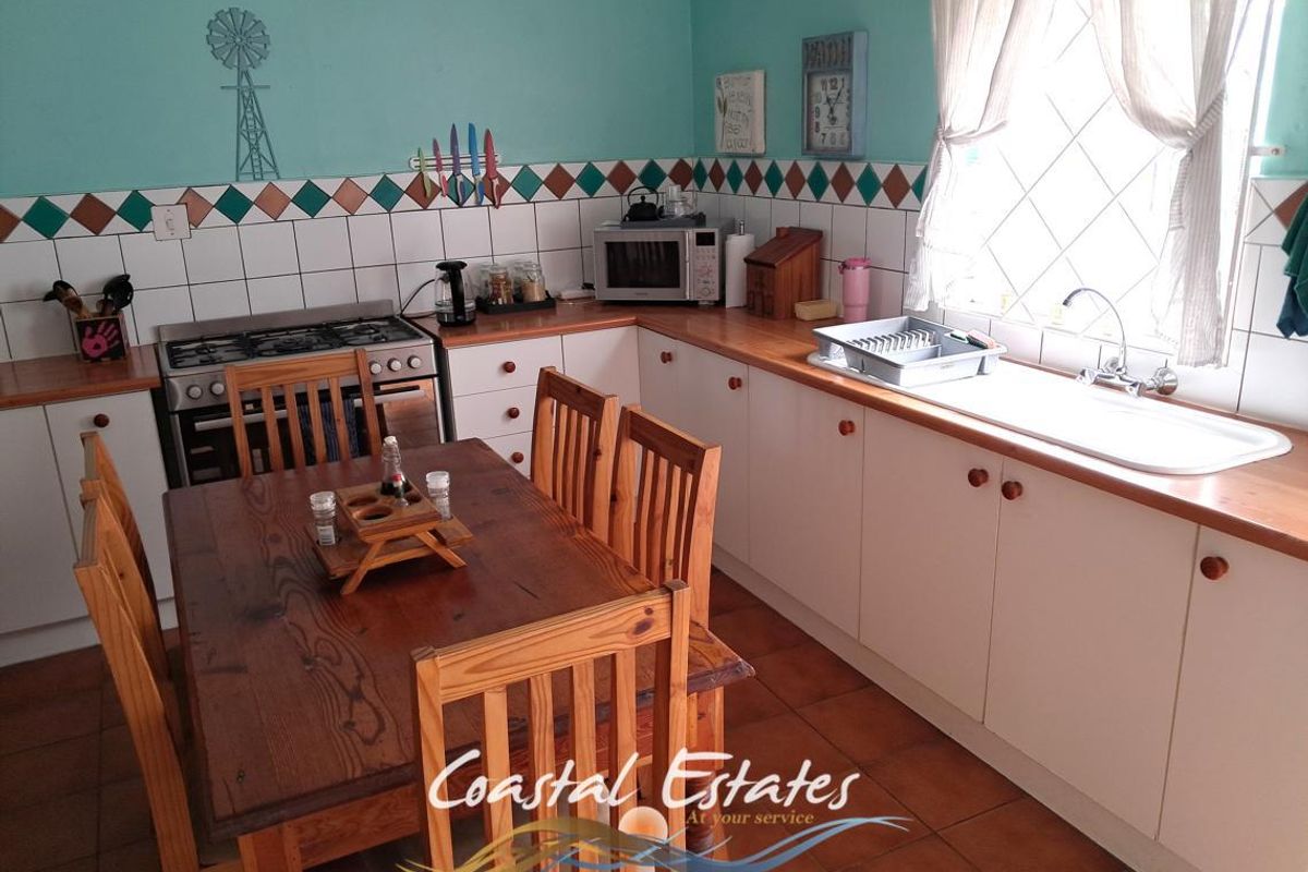 A functional kitchen featuring white cabinetry, wooden countertops, a gas stove, and a tiled splashback with a diamond pattern border.