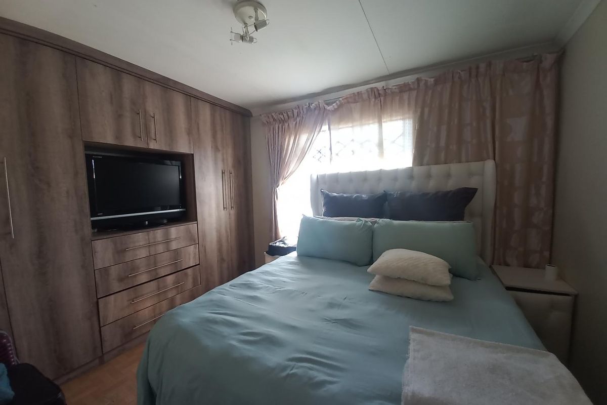 A cozy bedroom featuring extensive built-in wooden cabinetry with integrated storage and laminate flooring.
