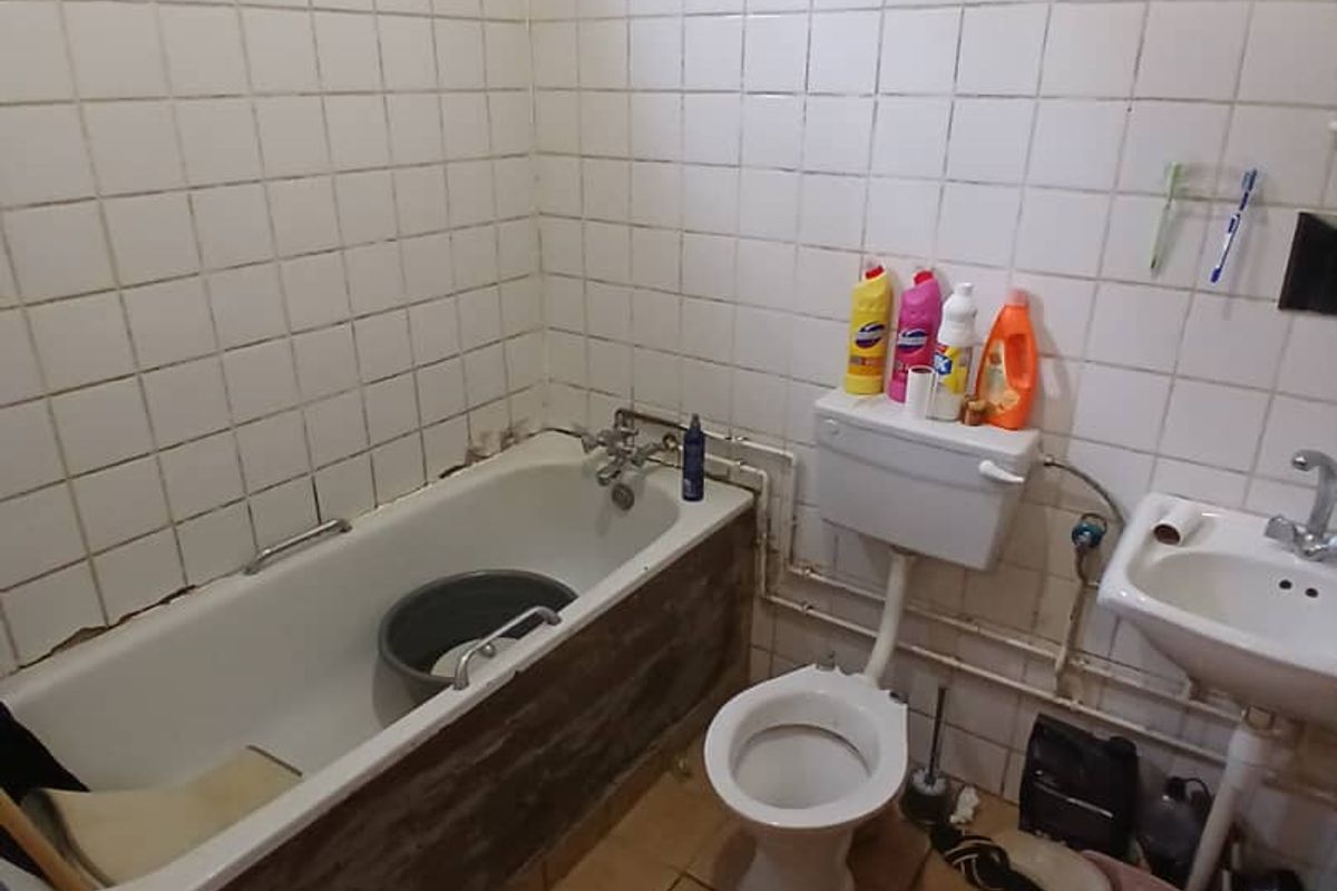 A dated bathroom featuring a bathtub, toilet, and pedestal basin with tiled walls and floors, requiring renovation and modernization of fixtures and finishes.