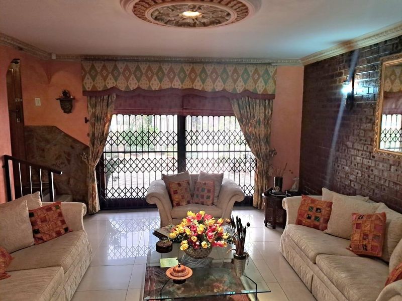 A living room featuring tiled flooring, an exposed brick feature wall, a decorative ceiling rose, and a security gate leading to the exterior.