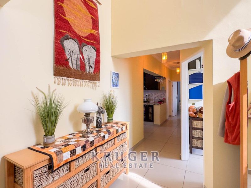 A bright hallway featuring tiled flooring and an archway leading through to the kitchen area.