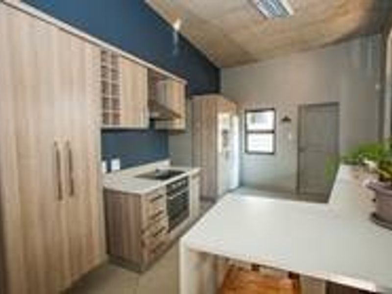 Modern kitchen featuring light wood cabinetry, stone countertops, integrated appliances, and a functional breakfast bar area.