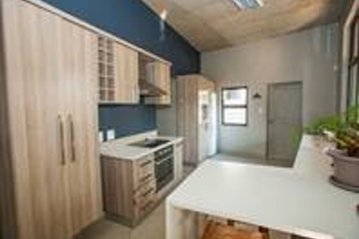 Modern kitchen featuring light wood cabinetry, stone countertops, integrated appliances, and a functional breakfast bar area.