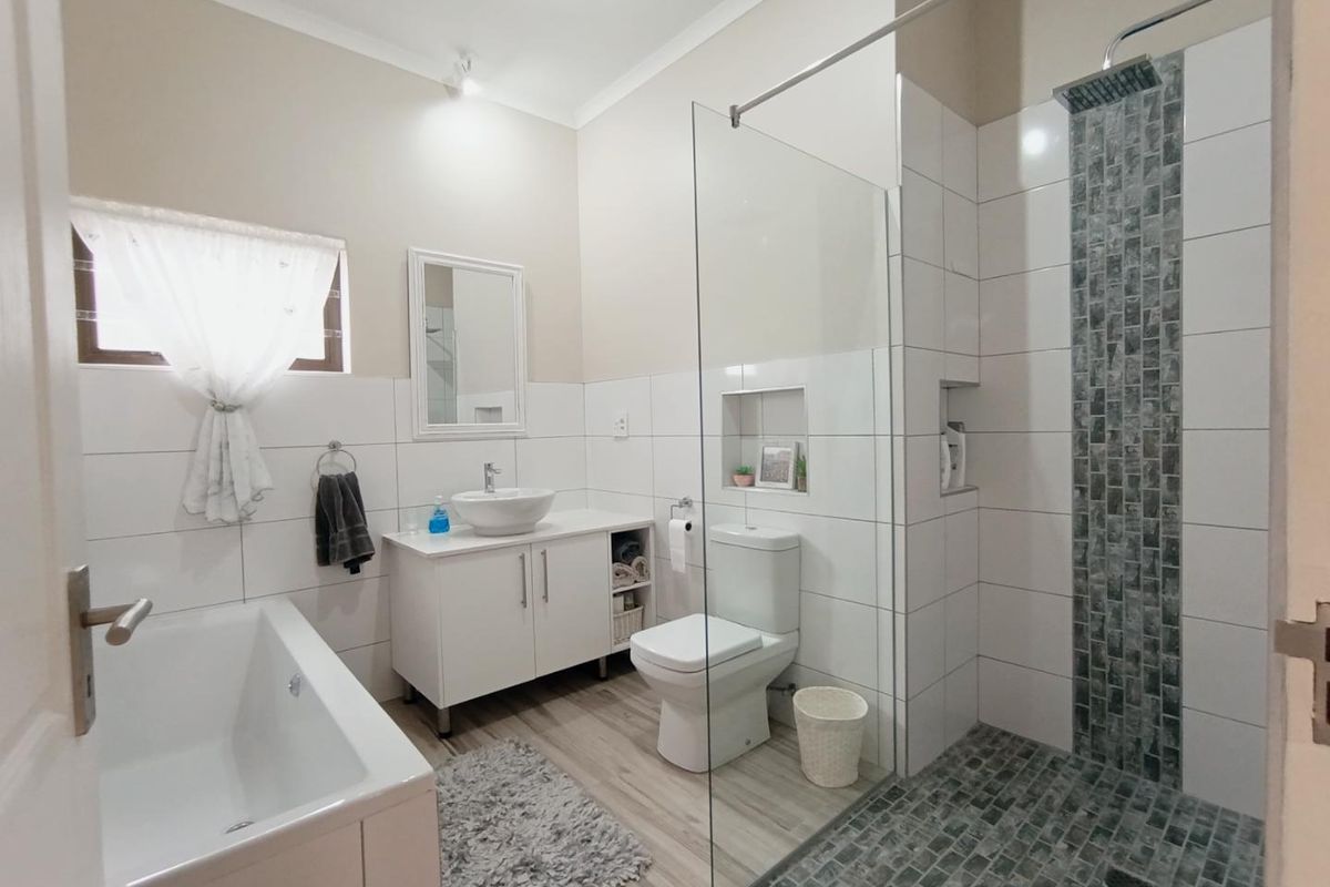 Modern bathroom featuring a walk-in shower with mosaic tile accents, a freestanding bathtub, a vessel sink vanity, and neutral wall finishes.