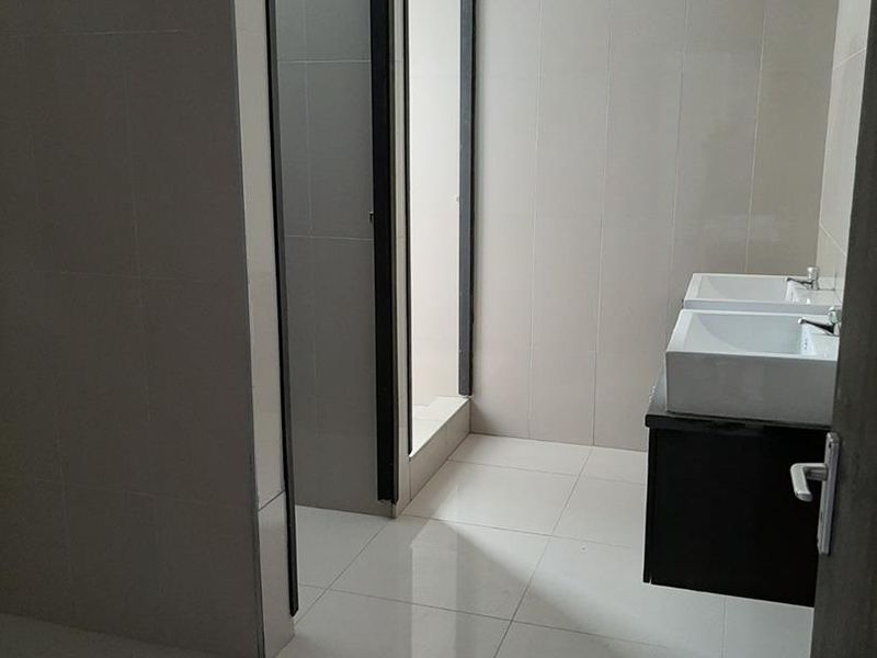 Modern bathroom featuring a double vanity with wall-mounted cabinetry, tiled walls and flooring, and a separate shower enclosure.