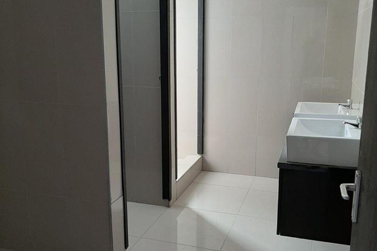 Modern bathroom featuring a double vanity with wall-mounted cabinetry, tiled walls and flooring, and a separate shower enclosure.