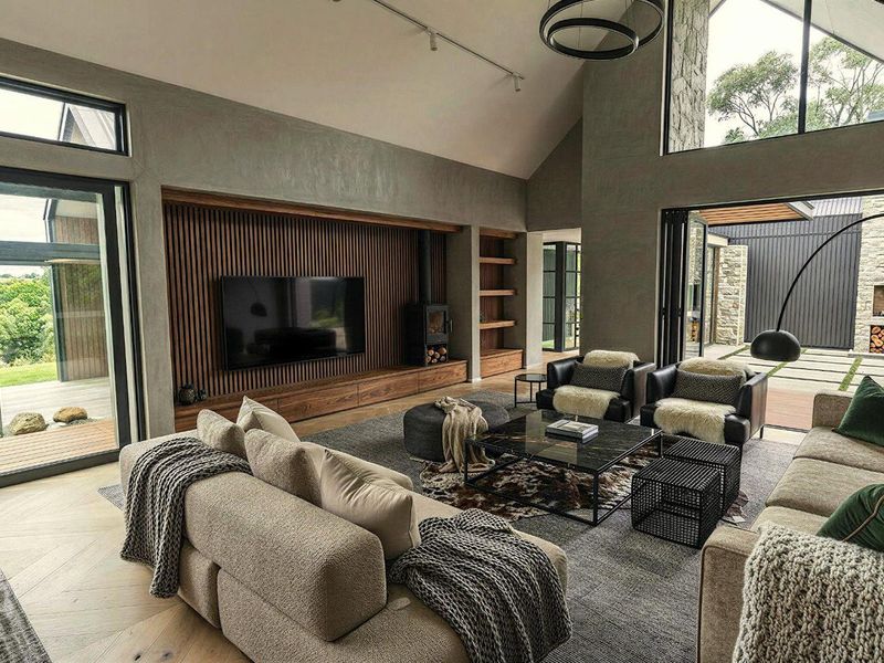 Spacious open-plan living area featuring high vaulted ceilings, timber slat feature wall, built-in fireplace, and large glass sliding doors opening to an outdoor patio.