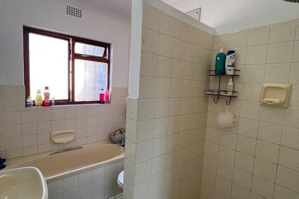 A functional bathroom featuring a separate shower enclosure with mosaic tile flooring, a bathtub, and a pedestal sink with tiled walls.