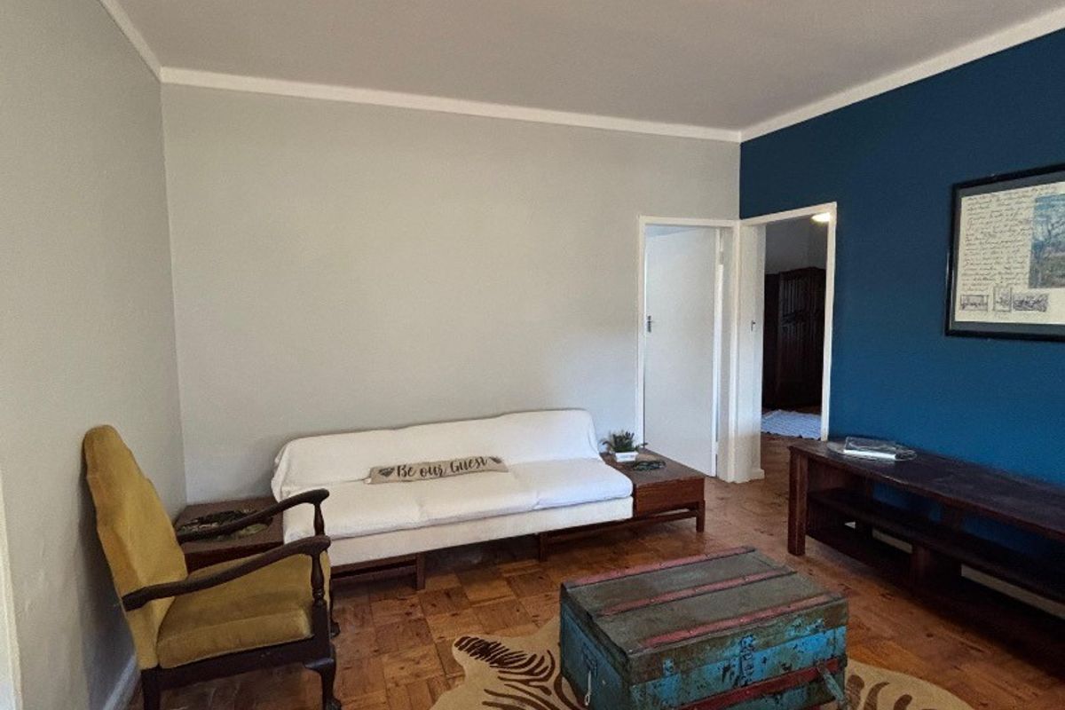 A living room featuring classic parquet flooring, a feature blue wall, and neutral grey walls with coving.