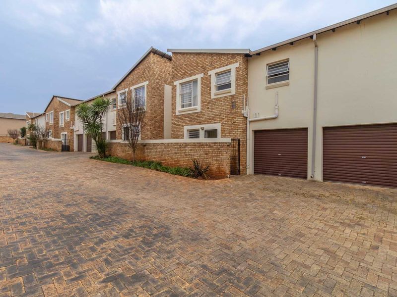 Exterior view of a townhouse complex featuring brick facades, paved driveway access, and secure roller garage doors.